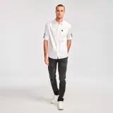 Camisa de manga larga convertible, color blanco, confeccionada en popelina. Cuenta con cuello clásico, cierre frontal con botones, bolsillo en el pecho con etiqueta de marca y mangas enrollables con pestaña de ajuste.