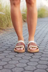 Sandalias bajas de cuero marrón y beige con tiras ajustables con hebilla.