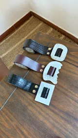 Cinto de cuero sintético con textura tipo cocodrilo, con hebilla de guampa plateada. Disponible en negro y marrón.