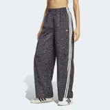 Pantalón Adidas Originals wide leg de satén, con estampado animal print en tonos grises y negros, cintura elástica y las clásicas tres tiras blancas a lo largo de los laterales.