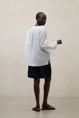 Blusa de lino blanca de corte amplio, con escote en V, mangas largas y puños con abertura y lazo.