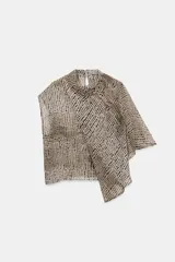 Blusa de cuello subido y manga sisa, confeccionada en tejido fluido semitransparente con estampado de lunares en tonos beige y negro. Presenta un diseño superpuesto tipo capa con caída asimétrica y cierre posterior con abertura y botón.