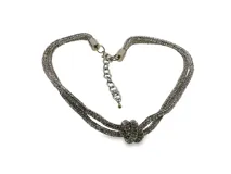 Gargantilla de metal plateado con diseño de nudo central y cuerpo tubular completamente cubierto de zirconias brillantes, con cadena de alargue y cierre de mosquetón.