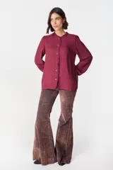 Camisa de color azul marino con cuello mao y detalle de volados a lo largo de la botonadura frontal. Presenta mangas largas con puños abotonados y un corte recto.