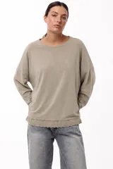 Remera de algodón color verde lima, de corte holgado y manga larga, con detalle de puntilla bordada en el ruedo.