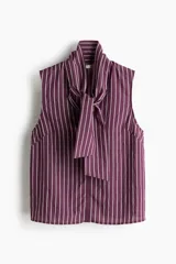 Blusa sin mangas color morado oscuro con finas rayas verticales en color claro. Presenta un cuello alto que se anuda al frente formando un lazo grande.