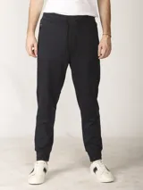 Pantalón de jogging color verde militar, corte slim, con puños elastizados en los tobillos y cordón ajustable en la cintura. Presenta un bolsillo lateral con cierre.