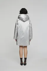 Campera reversible de corte regular, confeccionada en nylon con acabado repelente al agua. Presenta diseño con capucha, mangas raglán y cierre frontal con botones. Un lado es de color negro con bolsillos de parche, mientras que el reverso es de color plateado con bolsillos laterales integrados.