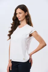 Blusa blanca sin mangas con volados en los hombros, cuello redondo con aberturas y cierre frontal parcial con botones.