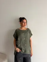 Blusa verde militar de manga corta, con cuello redondo y delicados bordados florales distribuidos en el frente.