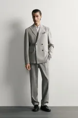 Blazer regular fit de Zara, confeccionada en tejido con mezcla de lana y algodón con diseño de cuadros grises. Cuenta con solapas de pico, doble botonadura cruzada, bolsillos con solapa en la cadera y bolsillo de vivo en el pecho.