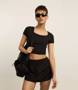 Remera deportiva Get Over de corte cropped y ajuste al cuerpo, confeccionada en microfibra con tacto suave. Presenta escote cuadrado y mangas cortas, ideal para actividades físicas.