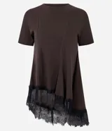 Remera de algodón color marrón oscuro, con cuello redondo, mangas cortas y diseño asimétrico. Presenta costuras decorativas en el frente y un detalle de encaje negro en el ruedo.
