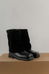 Bota de caña media combinada en cuero vacuno y gamuza, con diseño de solapa superior y punta cuadrada. Cuenta con suela de goma plana y tacón bajo.