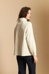 Camisa de pana color crema con cuello camisero con volados, cierre frontal de botones y mangas largas con puños abotonados. Presenta un bolsillo aplicado en el pecho y una silueta relajada.