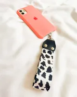 Llavero de tela con estampado animal print en blanco y negro, con enganche metálico plateado y aplique de cuero sintético negro.