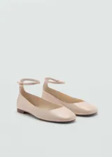 Zapato tipo bailarina con pulsera al tobillo y cierre de hebilla metálica. Presenta un acabado efecto charol y punta redondeada.