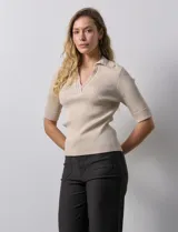 Buzo azul de tejido acanalado, con cuello solapa y escote en V en tejido calado.