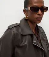 Campera estilo biker de poliuretano, con cierre frontal asimétrico, cuello con solapas y cremalleras en los puños. Presenta un diseño entallado con acabado liso.