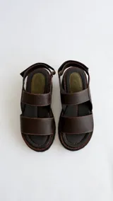 Sandalias de cuero con suela flatform track, tiras marrones y puntera con detalle de textura reptil en tono verde oliva. Cuenta con cierre de velcro en la tira trasera.