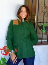 Chaqueta de paño de lana color verde, con cuello mao, cierre frontal de botones, bolsillos delanteros con solapa y detalle de parche de cuero en el hombro derecho.