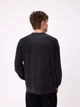 Sweater de cuello redondo y manga larga con diseño de hombros raglán, confeccionado en tejido de punto acanalado con efecto lavado. Presenta un pequeño logo bordado en el pecho.