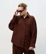 Camisa de corte sastre y diseño oversized, color marrón chocolate, con cuello clásico, cierre frontal de botones y puños largos. Confeccionada en tejido plano con caída estructurada.