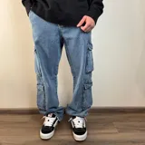 Jean cargo de corte baggy en color azul lavado, con múltiples bolsillos laterales tipo cargo y cierre frontal.