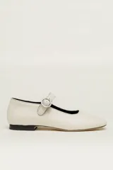 Zapato plano estilo Mary Jane de cuero color blanco roto, con punta cuadrada y tira ajustable con hebilla metálica redonda en el empeine.