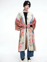 Kimono largo de rayón con diseño artístico estampado que combina motivos florales y figuras de aves. Presenta mangas amplias con detalles en contraste y corte abierto frontal.