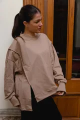 Buzo de felpa color camel con diseño asimétrico cruzado en el frente, cuello redondo y mangas largas con puños elastizados.