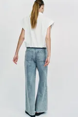 Jeans de tiro medio con pernera ancha, diseño wide leg y pinzas delanteras. Cuenta con bolsillos frontales, bolsillos traseros de plastrón y cierre frontal con cremallera y botón.