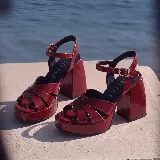 Sandalias de cuero color gris plateado con plataforma, taco ancho y tira ajustable al tobillo con hebilla metálica.