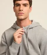 Buzo deportivo negro con capucha, cierre frontal con cremallera, bolsillos laterales y puños ajustados. Confeccionado en tejido de algodón y poliéster.