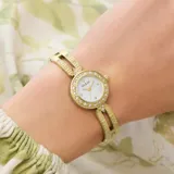 Reloj analógico Guess modelo Cassidy con caja y malla de acero inoxidable en tono dorado. Presenta una esfera blanca con acabado sunray, bisel decorado con cristales y diseño tipo brazalete.