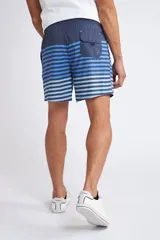 Short de baño con cintura elástica y cordón ajustable, confeccionado en tela ligera de secado rápido. Presenta un estampado botánico integral en tonos amarillos, blancos y azules, con dos bolsillos delanteros y uno posterior.