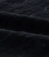 Camisa masculina negra de corte boxy, confeccionada en viscosa texturizada con efecto cutout. Presenta cuello solapa, manga corta y cierre abotonado frontal.