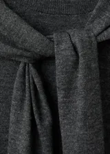 Jersey de punto fino color gris, con cuello redondo y una bufanda integrada del mismo género que cuelga al frente. Cuenta con diseño de manga larga y corte recto.