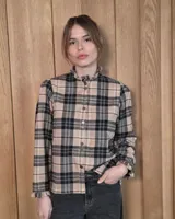 Camisa de algodón con estampado de rayas verticales finas, cuello alto con volados, cierre frontal con botones dobles y mangas largas con puños elásticos terminados en volados.