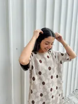 Vestido corto beige con estampado de flores marrones, corte holgado y mangas cortas.