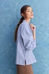 Camisa de rayas blancas y azules con cuello mao decorado con volados sutiles, cierre frontal de botones y mangas largas.