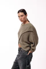 Sweater de punto con diseño cruzado frontal, de silueta amplia y mangas largas con puños ajustados. Presenta un corte holgado y textura suave.