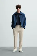 Pantalón chino de corte slim fit, confeccionado en tejido elástico. Presenta bolsillos frontales, bolsillos traseros de vivo con botón y cierre frontal con cremallera y botón.
