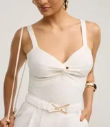 Top cropped blanco de tirantes anchos, confeccionado en tejido de punto texturizado, con escote en V y detalle de nudo o torcido en el centro del busto.