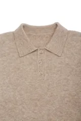 Sweater de punto con cuello polo y cierre frontal de botones. Presenta puños y ruedo acanalados, con un diseño de textura suave y abrigada.