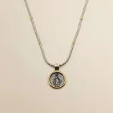 Collar con cadena de eslabones tipo serpiente en plata con detalles en oro, que sostiene un dije circular con la imagen de la Virgen Milagrosa en relieve, enmarcada en un borde de oro.