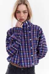 Chaqueta bomber de algodón con estampado a cuadros en tonos azules, amarillos y marrones, cuello alto y cierre frontal descentrado con botones. Cuenta con mangas abullonadas y puños elásticos.