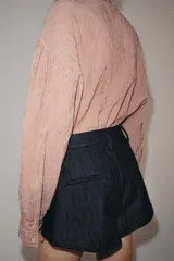 Camisa de algodón con estampado de rayas verticales, cuello subido con lazada frontal, manga larga abullonada y puños ajustados.