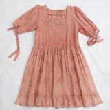 Vestido a la rodilla blanco y rosado, con bordado floral en el escote, mangas 3/4 con lazo y falda fruncida.