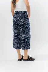 Pantalón de corte culotte y tiro medio, confeccionado en viscosa con estampado de hojas blancas sobre fondo color miel. Presenta una silueta amplia y fluida, con cintura elástica en la parte posterior y bolsillos laterales.